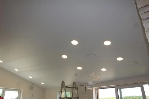Stretch ceiling with multiple recessed lights and a chandelier Stock Photos