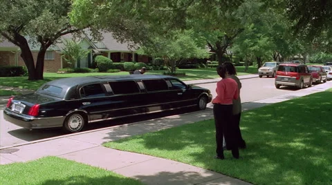 Stretch limo driving away as three people on a lawn wave good-bye and turn away Stock Footage 59545668
