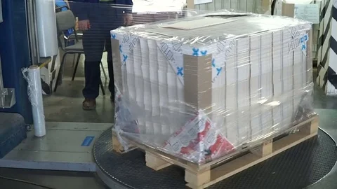 Stretch wrapping machine putting cling wrap around cargo on palettes Stock Footage 74108277