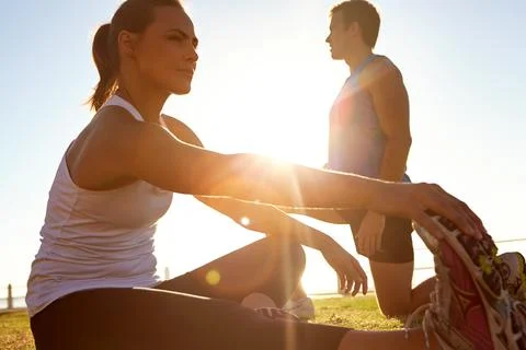 Stretch your limits. a man and a woman stretching on the grass. Stock Photos