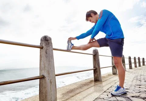 Stretch...and avoid injury. Full length shot of a young male jogger stretching Stock Photos
