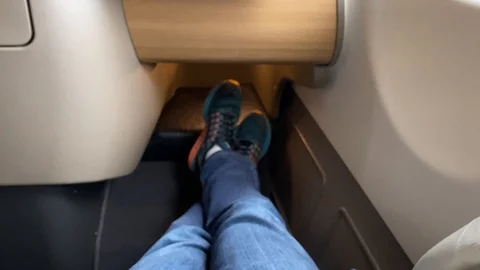 Stretched legs, inside the business class seat at the airplane, 4k Stock Footage 124486636