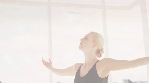 Stretching dancer in black leotard lifting arms and folding into seated pose in Stock Footage 332505389