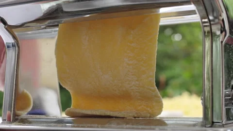 Stretching home made dough on a rolling machine. Preparation of thin dough fo Stock Footage 142836358