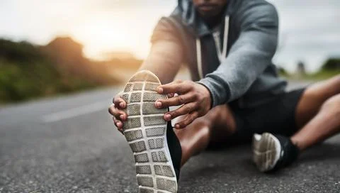 Stretching out those hamstrings. a handsome young sportsman warming up for a Stock Photos