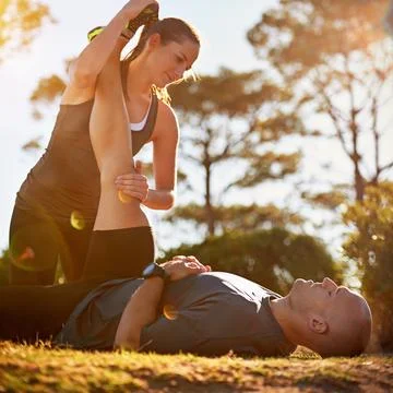 Stretching out those hamstrings. a young couple stretching together outside. Stock Photos