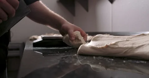 Stretching pizza dough in the back of a kitchen and cutting it into balls Stock Footage 104963782