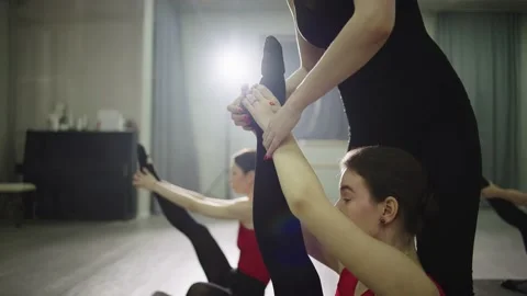 A stretching trainer helps you stretch your leg to your head. Stock Footage 237619488