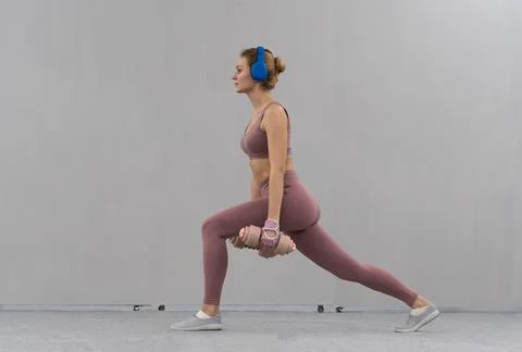 Stretching using dumbbells with hands down young girl losing weight at home Stock Photos