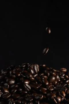 Strewing coffee beans falling down concept on dark background Stock Photos