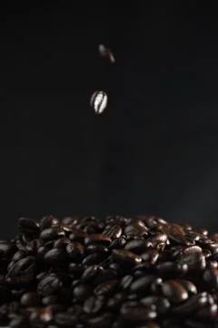 Strewing coffee beans falling down concept on dark background Stock Photos