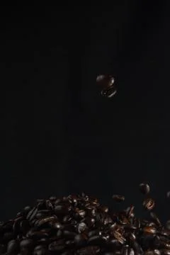 Strewing coffee beans falling down concept on dark background Stock Photos