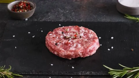 Strewing pepper on raw beef burger patty on dark background Stock Footage 196612796