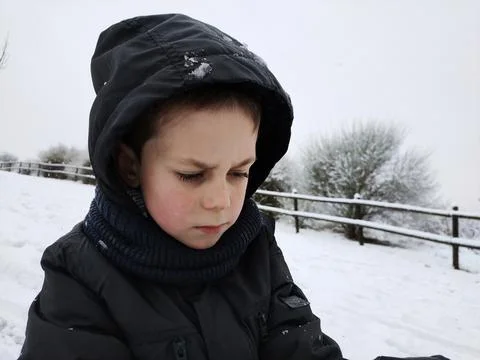 Strict boy in capishon in winter on a background of snow Stock Photos