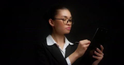 A strict brunette on an isolated black background signs documents. Stock Footage 194775332