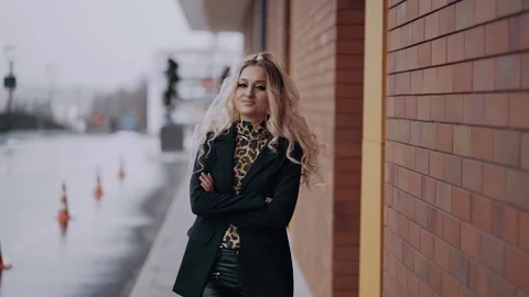 The stridently made-up blonde confidently puts her hands, crossing them on her Stock-Footage 157557637