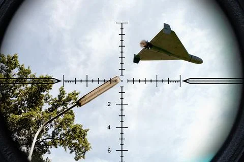 Strike drone appears in optical scope view above urban infrastructure and o.. Stock Photos