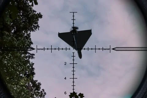 Strike drone appears in optical scope crosshair against sky and trees backg.. Stock Photos
