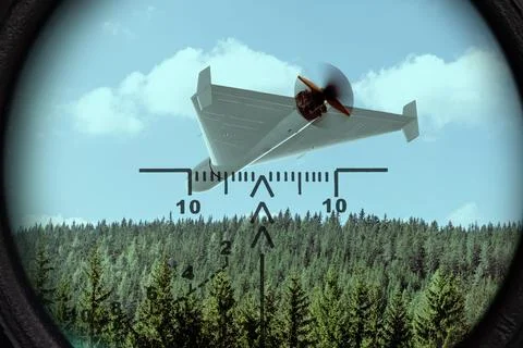 Strike drone flies above forest area and appears in center of targeting ret.. Foto stock
