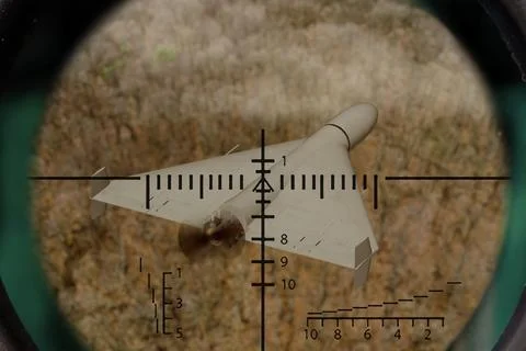 Strike drone observed through optical scope above area with dry vegetation. Stock Photos