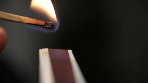 Strikes a match on the side of the box. Smoke and fire appear. Stock Footage 263846176