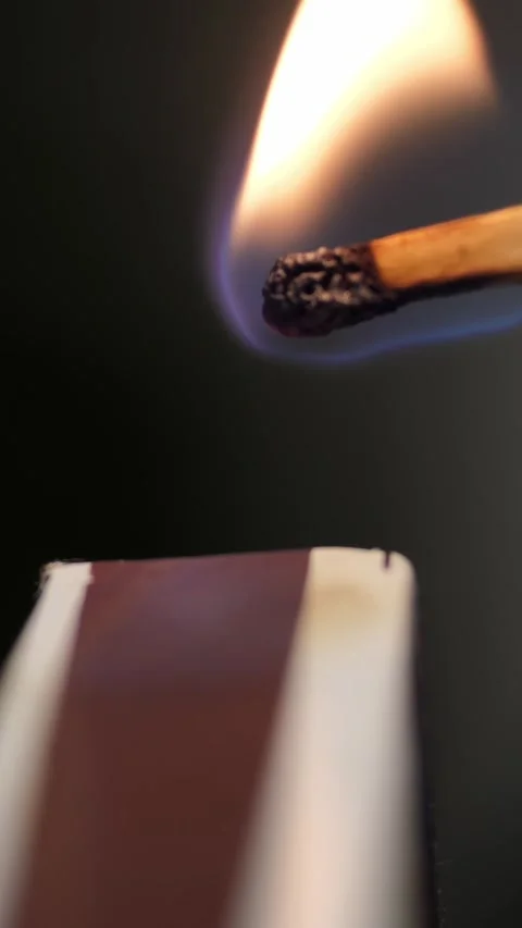 Strikes a match on the side of the box. Smoke and fire appear. The flame ignites Stock Footage 324791404