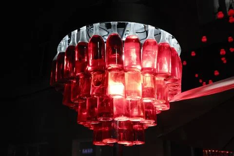 A striking chandelier crafted from countless ruby red bottles 库存照片