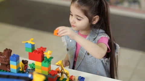 Striking girl plays with plastic objects, blocks of children's designer Video stock 87960727