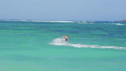 Striking Pan Following Man Gracefully Wind Surfing on Turquoise Water on Sunny D Stock Footage 149290184