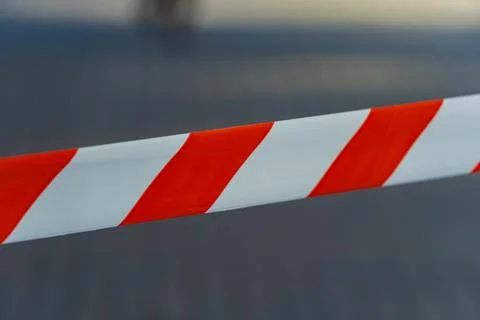 A striking pattern of red and white caution tape stretches across an open a.. Stockfoto's