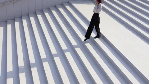 Striking patterns emerge as a figure walks gracefully on sunlit stairs Vídeos de archivo 295276161
