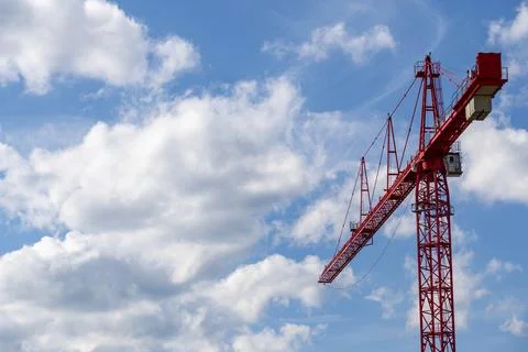 A striking red construction crane set against a vibrant blue sky Foto stock