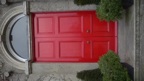 A striking red door with unique design amidst lush greenery Stock Footage 289754575
