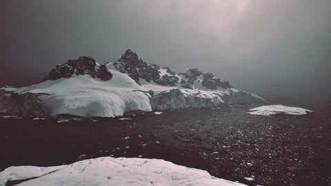 Striking scene of mountain ridge piercing icy glacier beneath heavy clouds Stock Footage 339618846