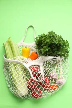String bag with different vegetables on light green background, top view Foto stock