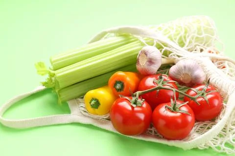 String bag with different vegetables on light green background, closeup Foto stock