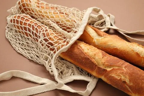 String bag with fresh baguettes on brown background, closeup Stock Photos