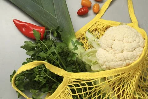 String bag with fresh vegetables on gray background, flat lay Stock Photos