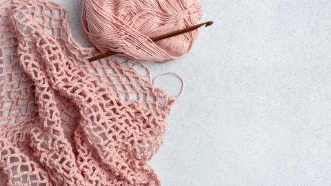 String bag in the process of knitting. Delicate pink mesh bag, crochet hook a Stock Photos
