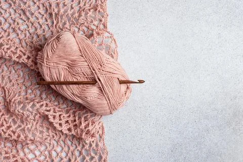 String bag in the process of knitting. Delicate pink mesh bag, crochet hook a Stock Photos