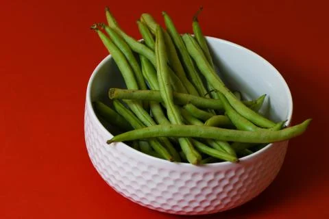 String beans fresh green closeup in cup on isolated red background Stock Photos