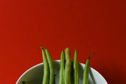 String beans fresh green closeup in cup on isolated red background Stock Photos