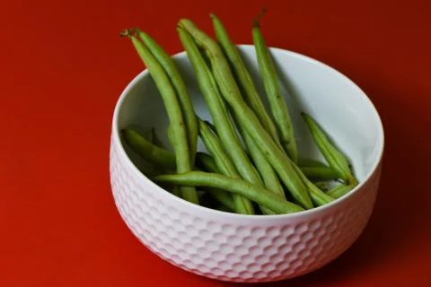 String beans fresh green closeup in cup on isolated red background Stock Photos