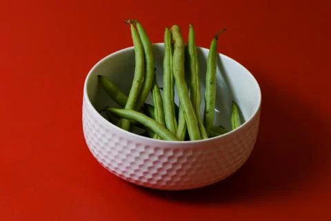 String beans fresh green closeup in cup on isolated red background Stock Photos