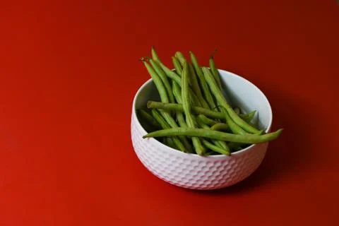 String beans fresh green closeup in cup on isolated red background Stock Photos