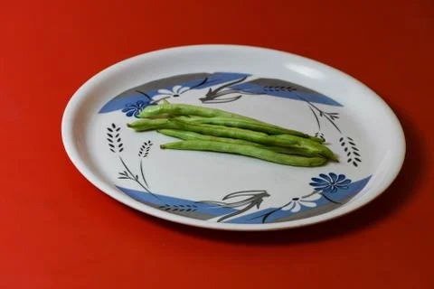 String beans on plate close on isolated red background Stock-Fotos