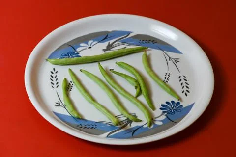 String beans on plate close on isolated red background Stock-Fotos