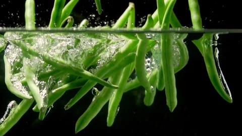 String beans splashing into water on black background  super slow motion 動画素材 117012628