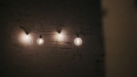 String of bright lights hanging on white brick wall Stock Footage 238510766