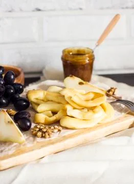 String Cheese, honey, grapes, pears and nuts on wooden board on kitchen Stock Photos